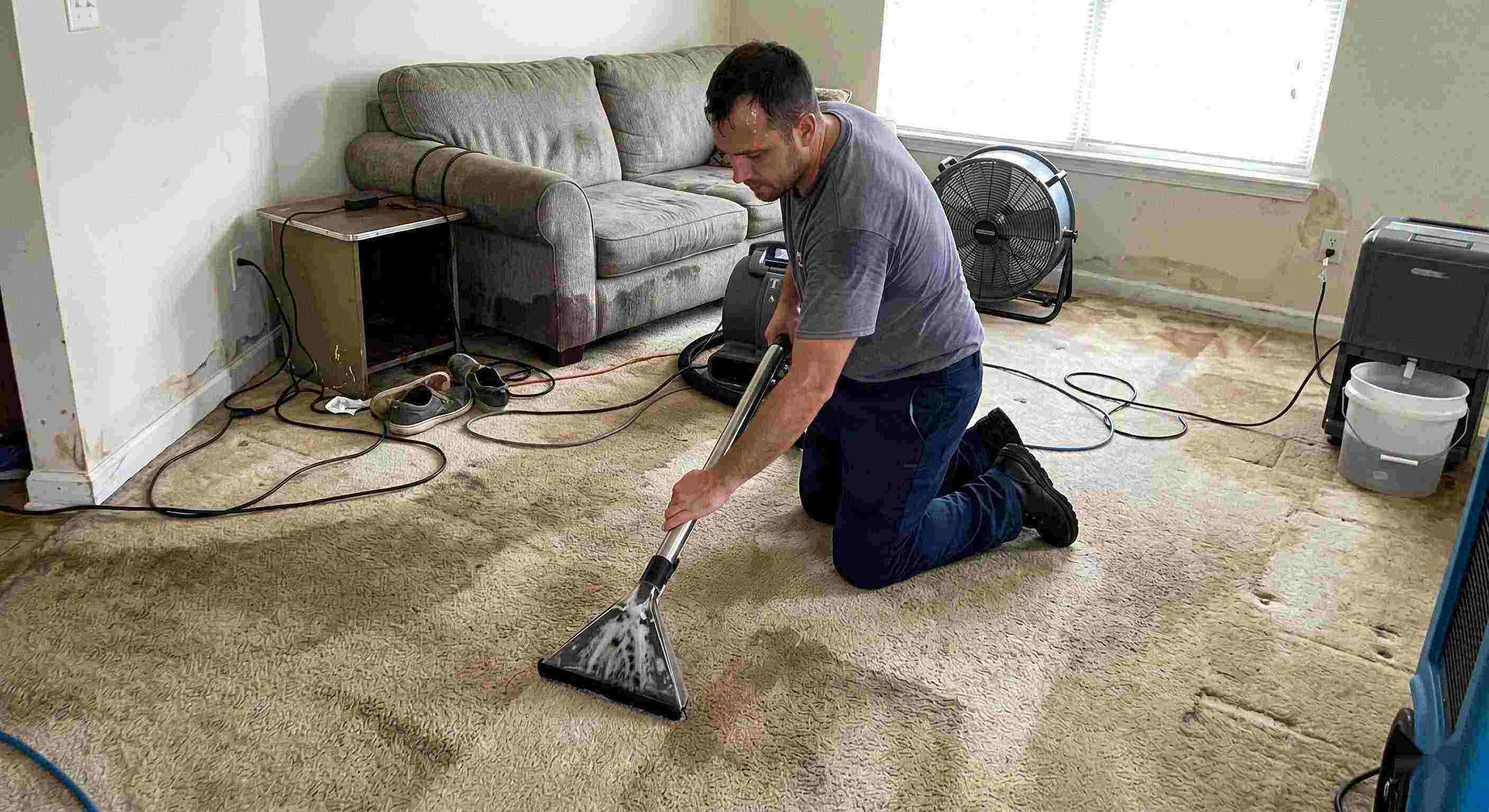 Technician performing carpet water extraction in a residential home using professional equipment after water damage in Wichita