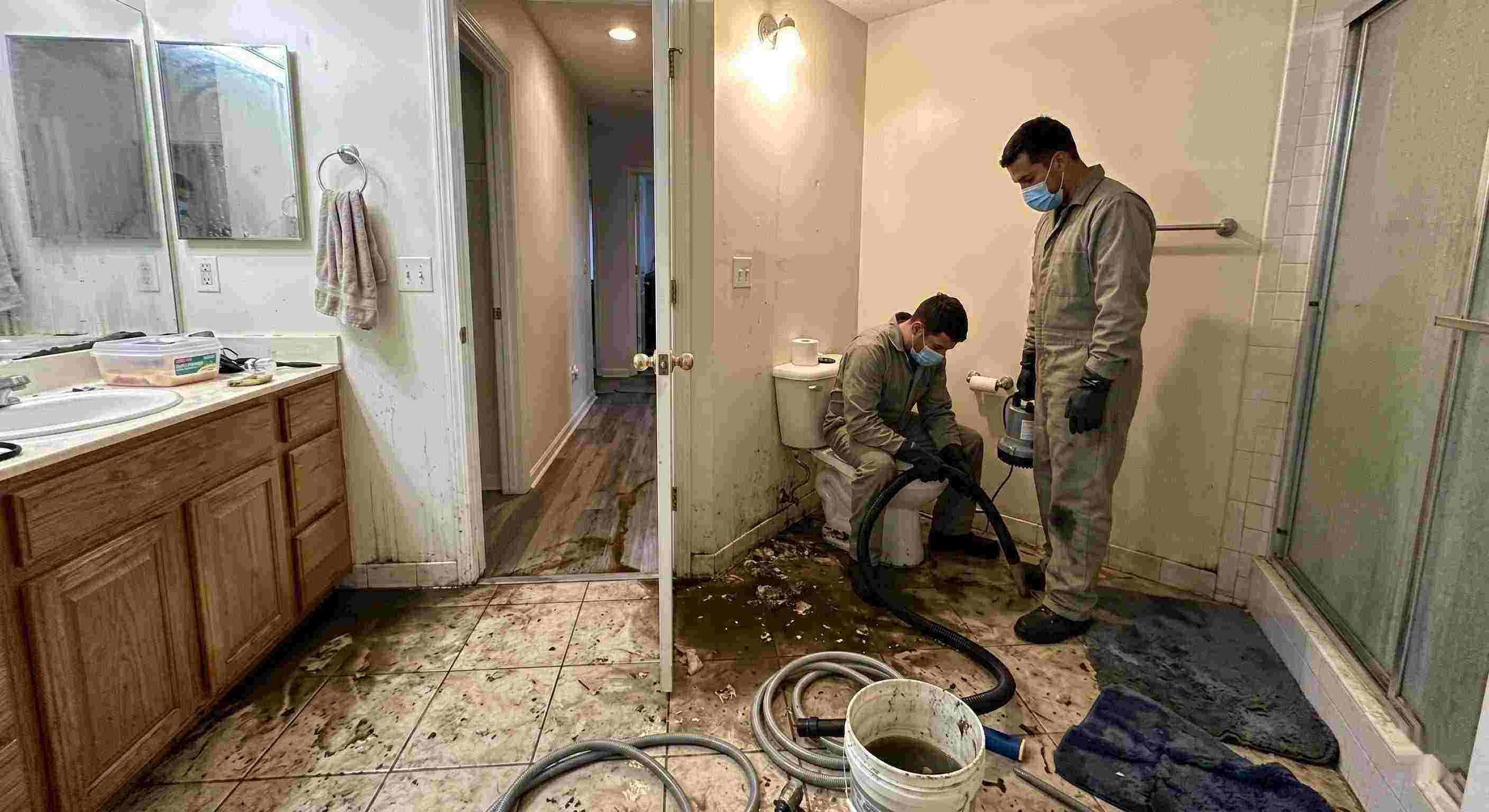 Septic tank backup cleanup in Wichita bathroom with technicians removing contaminated water and sanitizing affected areas