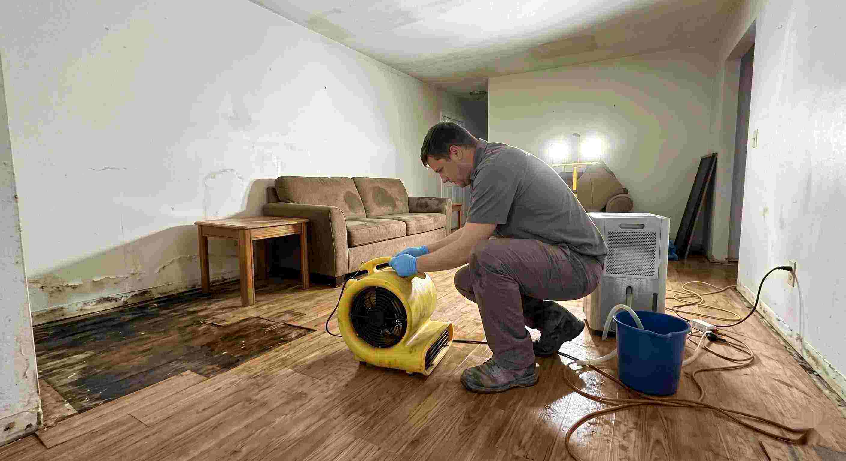 Trusted water damage restoration technician drying wet floors with equipment during cleanup process in Kansas City